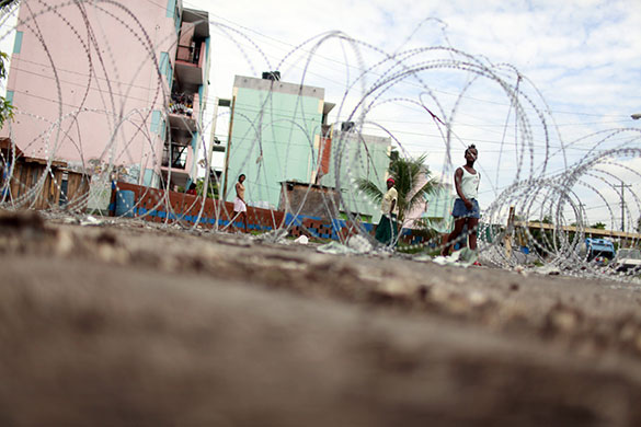 24 hours: Kingston, Jamaica: A girls walks next to barbed wire at a checkpoint