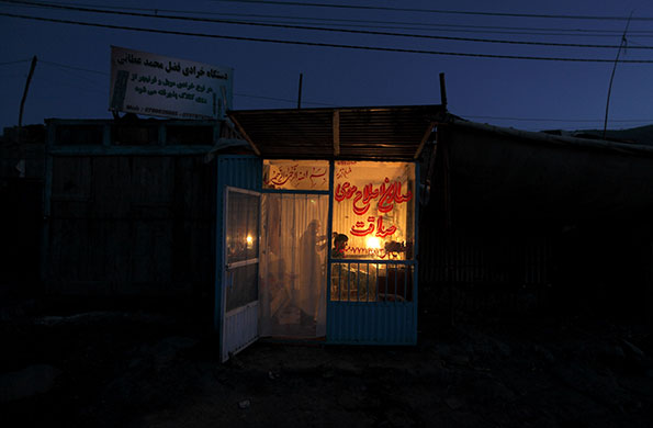 24 hours: Kabul, Afghanistan: A man gets a haircut as the day ends