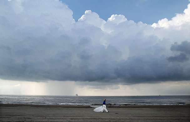 24 hours: Louisiana, USA: A worker leaves the beach as a storm approaches Grand Isle