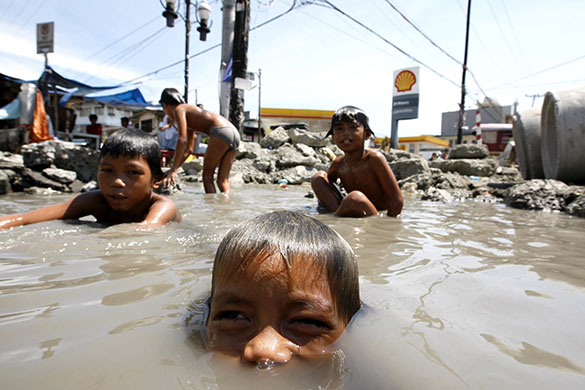 24 hours: Manila, Philippines: Filipino children swim in a road construction site