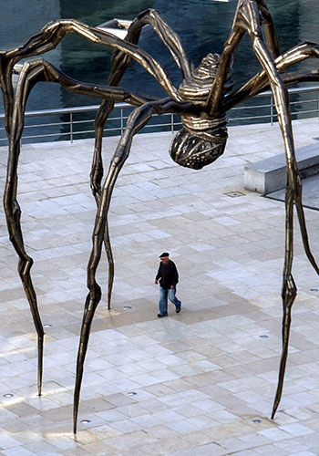 A man walks under Maman at the Guggenheim in Bilbao, Spain