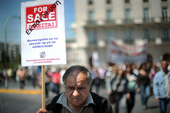 Greece: A teacher carries a banner which translates as 'Education for sale'