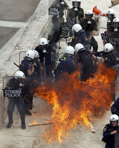 Strike in Greece: Riot police react to a molotov cocktail as it explodes on a bridge