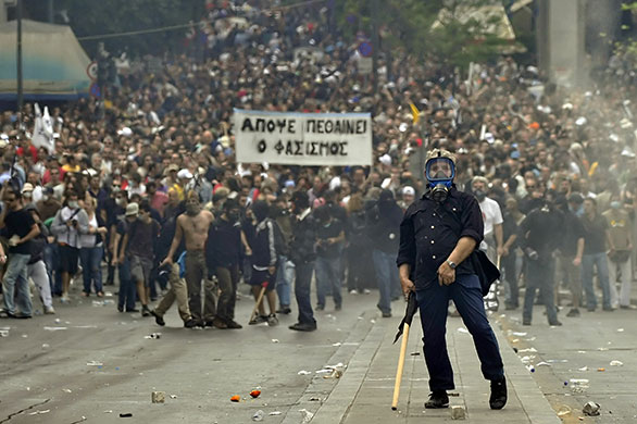 Greece Rioting: A protestor gestures to police near the Parliament building in Athens
