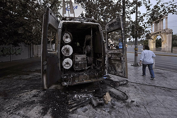 Greece Rioting: People walk around burnt out Ihlas turkish international news agency van