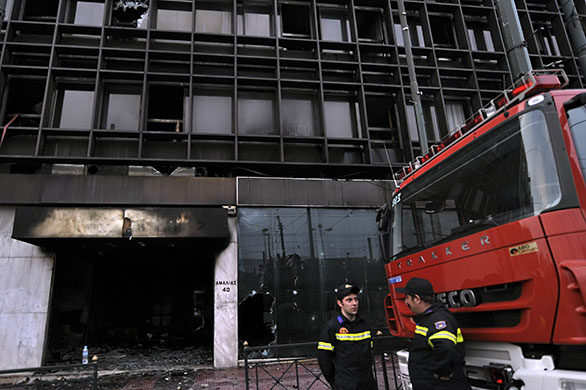 Greece Rioting: Firemen stand by the burnt Ministry of Economy offices building
