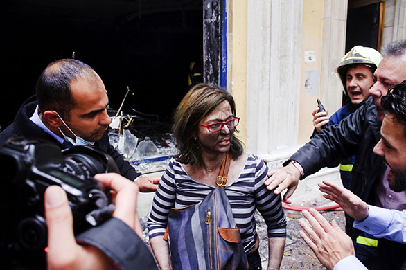 Week in business: A bank employee reacts after being rescued from a fire in an Athens bank