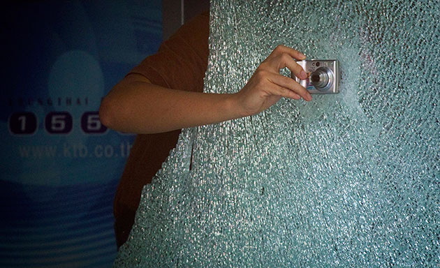 24 Hours in Pics: Thai forensic policeman photographs the damaged exterior of a bank