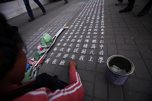 24 Hours in Pics: A Chinese girl writes notes on the ground as she begs for money
