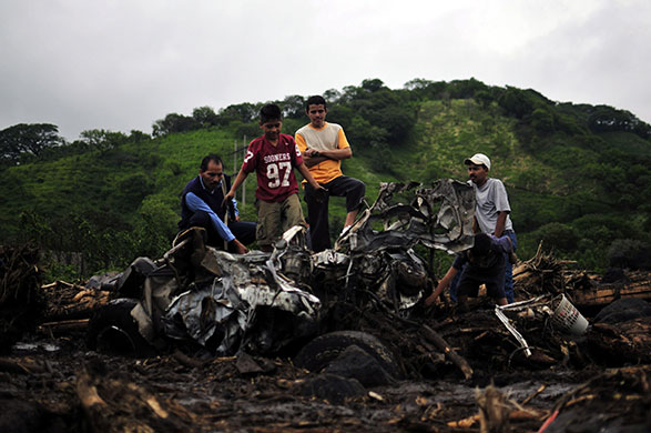 Guatemala storm: 30 May: Children and adults look at a destroyed car