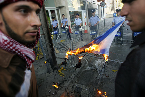 Israel protests: Palestinians protesters stand in front of police officers in Nicosia