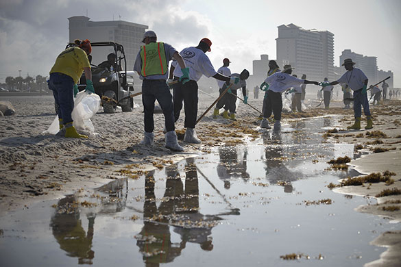 Week in Business: Workers clean up the oil washed ashore from the BP Deepwater Horizon spill.