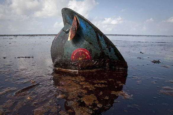 Week in Business: A oil worker's hard hat lies in oil from the Deepwater Horizon oil spill