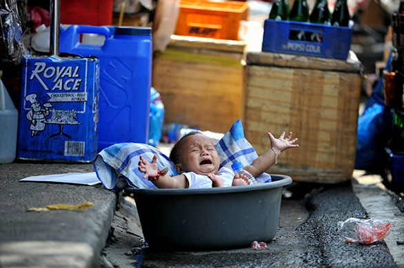 24 hours: Manila, Philippines: A child in a water bowl cries at the Divisoria market 
