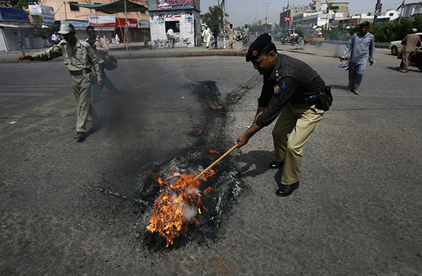 24 hours: Karachi, Pakistan: A policeman tries to remove burning tyres