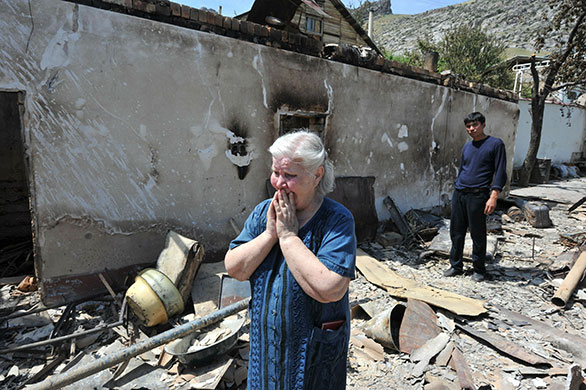 Kyrgyzstan violence: An Ethnik Uzbek woman cries beside the wreckage of her home in Osh 