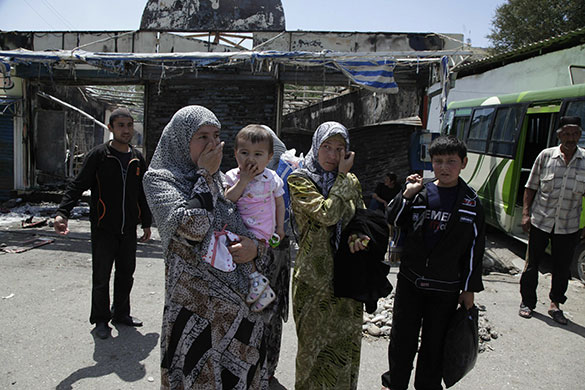 Kyrgyzstan violence: Ethnic Uzbeks stand near the burned out bus station in Osh