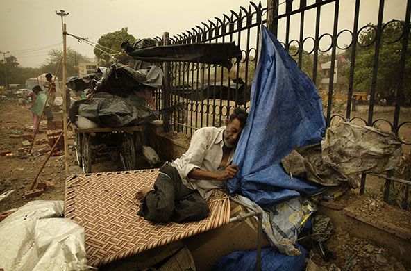 24 hours in pictures: New Delhi, India: A homeless man takes shelter from a dust storm