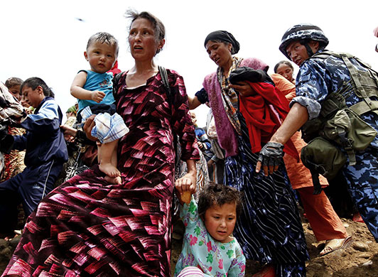 Uzbek refugees: A Kyrgyz soldier directs Uzbek refugees