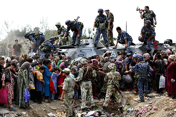 Uzbek refugees: Refugees line up around an armoured vehicle in the Kyrgyz city of Osh