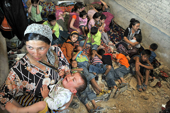 Uzbek refugees: A mother holds her son as they wait inside a house