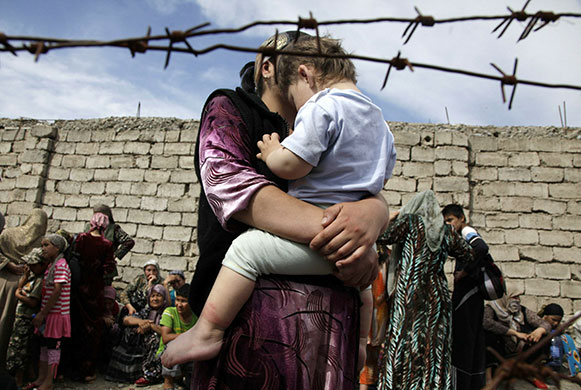 Uzbek refugees: A mother holds her son as they wait at the Kyrgyz-Uzbek border