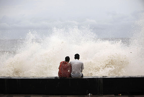 24 hours in pictures: A couple sits at a seafront during high tide in Mumbai