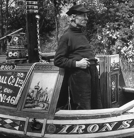 Longden's Canals: An old man in a captain's hat stands at the helm of his boat