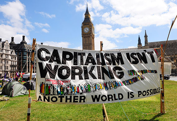 Week in business: A banner depicting a job centre queue stands in the Democracy Camp 