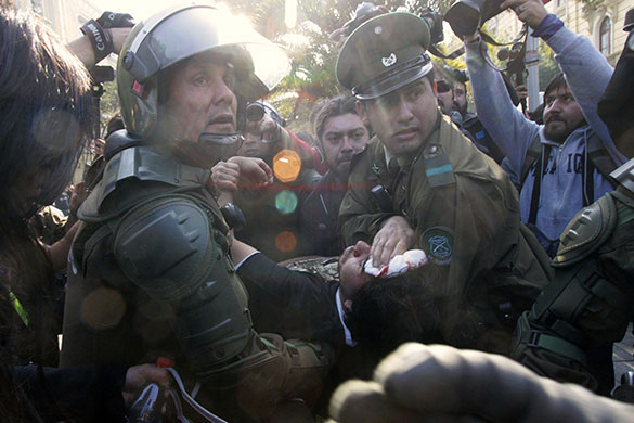 24 hours in pictures: Santiago, Chile: Policemen carry an injured freelance photographer