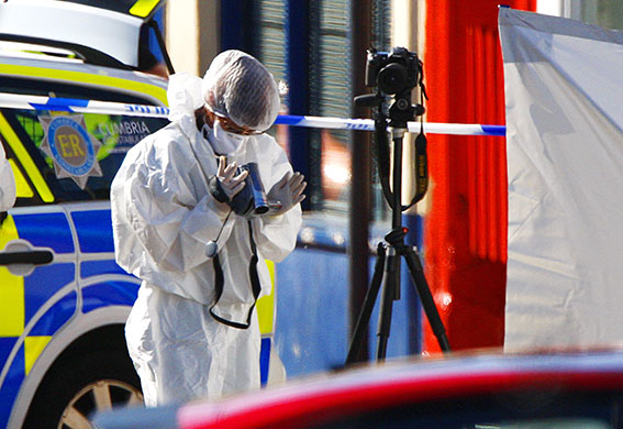 Cumbria shootings: A police forensics team member records evidence at a murder scene
