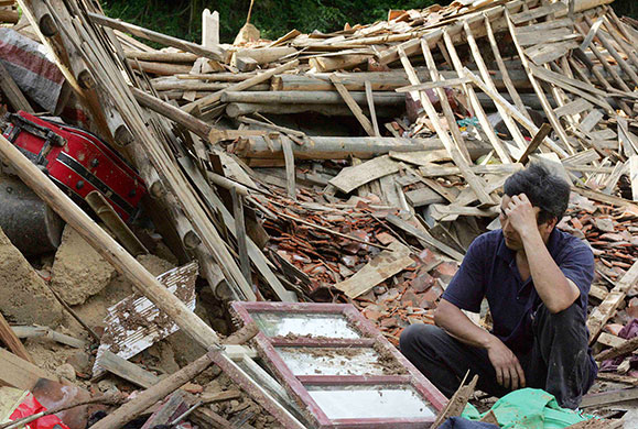 Chian flooding: A resident looks on as he squats in the debris in Taolin village, China