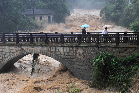 Chian flooding: Residents walk on a bridge over an overflowing river at Xiqin, China