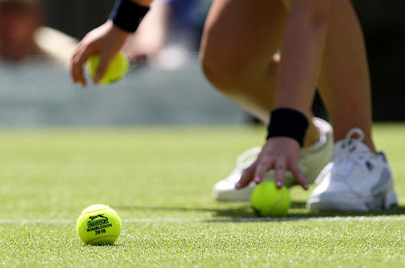 wimbledon atmosphere: A ball girl picking up  tennis balls during a match