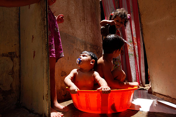 24 hours in pictures: Baghdad, Iraq: Children use a plastic tub to cool themselves