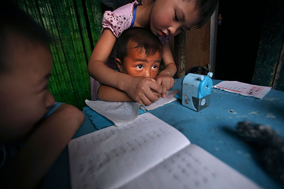 24 hours in pictures: Beijing, China: A Chinese girl shows a younger child how to write