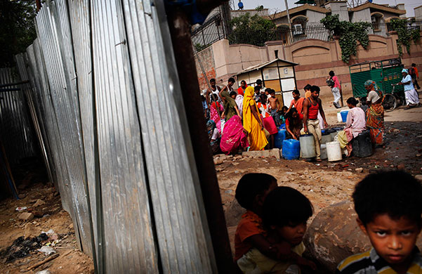 24 hours in pictures: Indians wait their turn to fill containers at a water depot at a slum