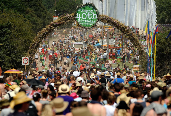 Glasto day three: Revelers walk under an arch marking 40 years of the festival