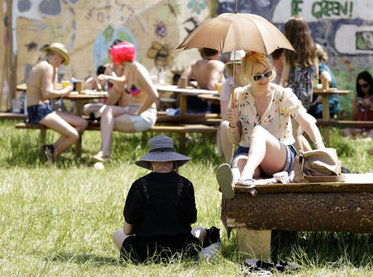 Day Four: Festival-goers shelters from the sun under an umbrella at Glastonbury