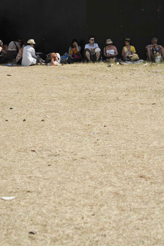 Heat: Festival-goers seek shade by a fence 