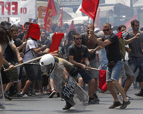 Greece protests: Protesters beat a riot policeman during a rally in Athens