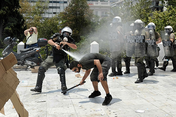 Greek protests: A protester clashes with riot police in front of the parliament in Athens