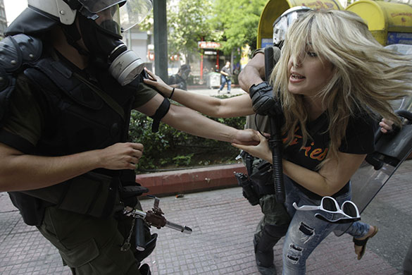 Greek protests: A riot policeman pushes away a protester