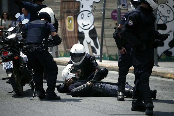 Greek protests: A riot police officer helps an injured colleague