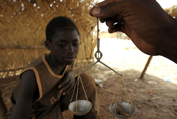 24 hours: Namisgma, Burkina Faso: A dealer weighs a young gold miner's finds