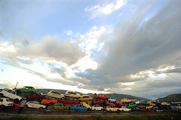 24 hours: Skopje, Macedonia: A man stands in front of an old car dump on a road