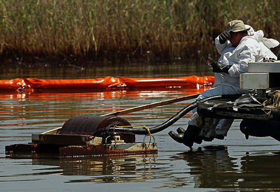 Week in Business: Contract workers from BP use skimmers to clean oil from a marsh