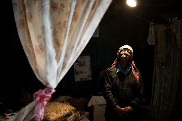 24 hours in pictures: Cape Town, South Africa: A woman stands in her home in Blikkiesdorp