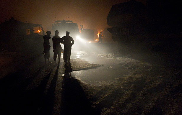 Pakistan convoy attack: Men stand silhouetted near vehicles