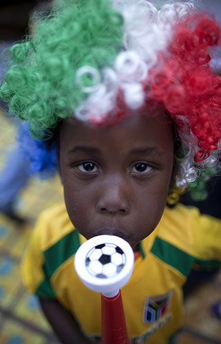 World Cup parade: Aboy wearing a wig with the Mexican flag colors blows a vuvuzela